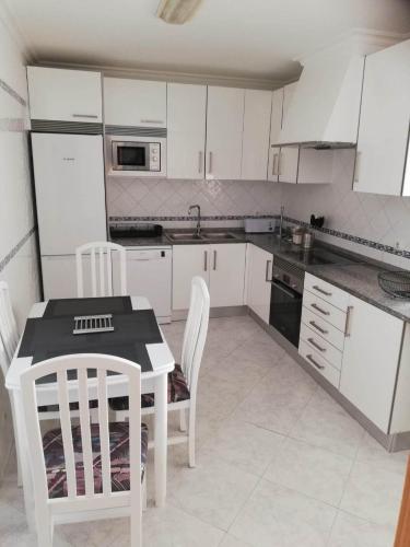 a kitchen with white cabinets and a table and chairs at Apartamento Saint Martin in Armação de Pêra