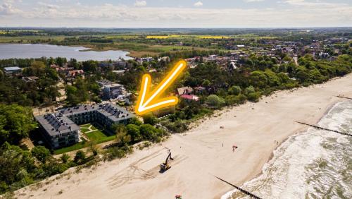Boho przy plaży - Rezydencja Niechorze في نيخوجة: إطلالة علوية على شاطئ به علامة نيون كبيرة