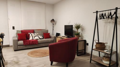 un soggiorno con divano e sedia rossa di Casa FotoStudi37 a Deltebre