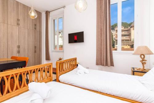 - 2 lits dans une chambre avec un bureau et une fenêtre dans l'établissement Luxury 3 Bd Aptment with Sea view, à Cannes