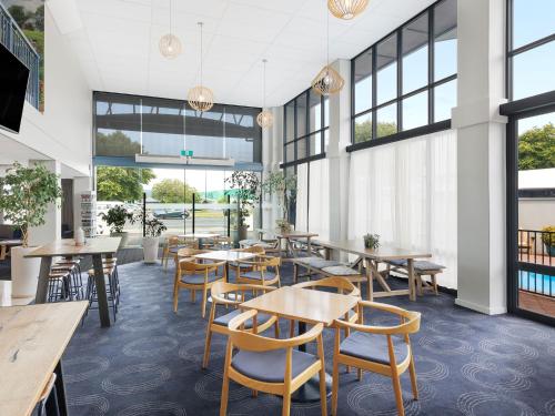 a restaurant with tables and chairs and windows at JetPark Hotel Rotorua in Rotorua