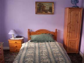 a bedroom with a wooden bed and a dresser with a night stand at Ye Olde Station Guest House Birmingham, Shustoke in Shustoke