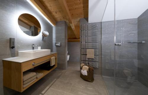 uma casa de banho com um lavatório e um chuveiro com um espelho. em Aparthotel Grischuna em Samnaun