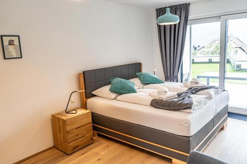 een slaapkamer met een bed en een groot raam bij Top 5 Alpe Maritima - Traumhafte Ferienwohnung mit Seeblick und Bergkulisse am Ossiacher See in Annenheim