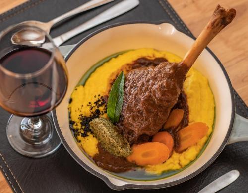a bowl of food with meat and vegetables and a glass of wine at Pampa Lodge, Quincho & Caballos in Torres del Paine