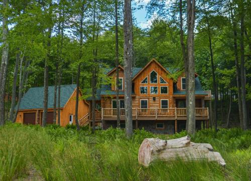 a large wooden house with a deck in the woods at Big Log Lodge in McHenry