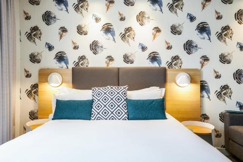 a bedroom with a bed and a wall with shells at Holiday Inn Perpignan by IHG in Perpignan