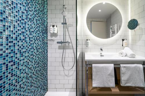 a bathroom with a shower and a sink and a mirror at Holiday Inn Perpignan, an IHG Hotel in Perpignan