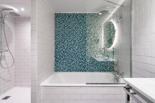 a bathroom with a tub and a green tile wall at Holiday Inn Perpignan by IHG in Perpignan
