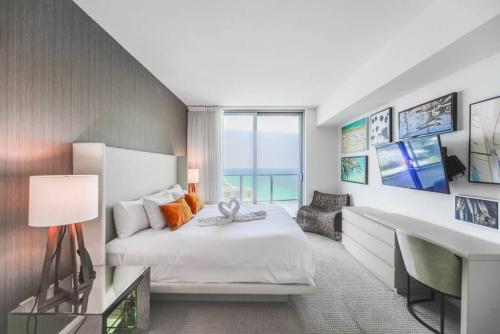 a bedroom with a white bed and a desk and a desk at Spectacular Sunset Views Over the Ocean at Hollywood in Hollywood