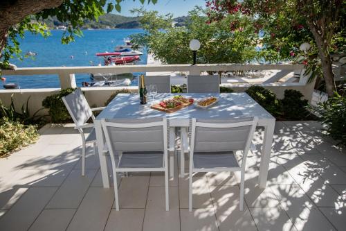 a table and chairs on a patio with a view of the water at House Šubić in Supetarska Draga