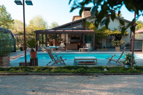 une piscine avec des chaises et un gazebo dans l'établissement Villa des gones, à Dommartin
