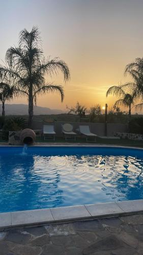 a swimming pool with a sunset in the background at Etnadia in Santa Maria di Licodia