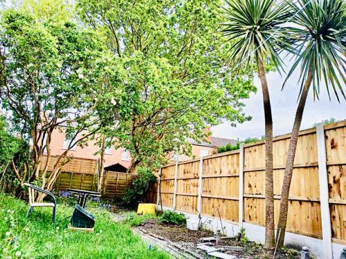 a fence in a backyard with a palm tree at Traditional English House in Derby