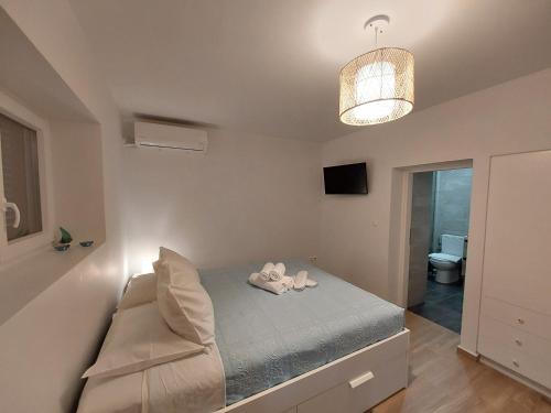 a small bedroom with a bed and a chandelier at Sweet & Cosy Αpartment in Chora's old town in Andros