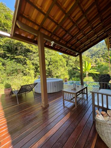 a wooden deck with a bench and a table at Cactus Chalé em lumiar in Lumiar