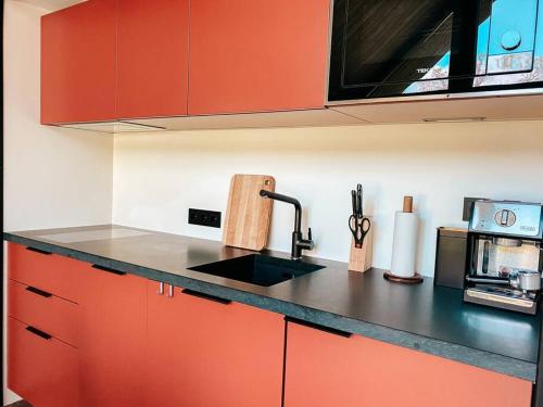 a kitchen with red cabinets and a black counter top at Private Stay Zen House to unplug and recharge in Tuimõisa
