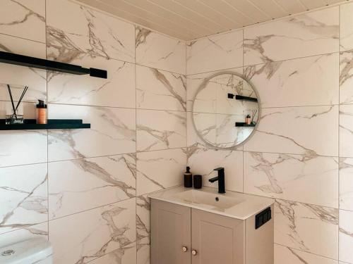 baño con paredes de mármol, lavabo y espejo en Private Stay Zen House to unplug and recharge, en Tuimõisa