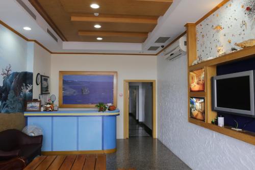 vestíbulo con barra azul y TV de pantalla plana en Goden Beach B&B, en Eluan