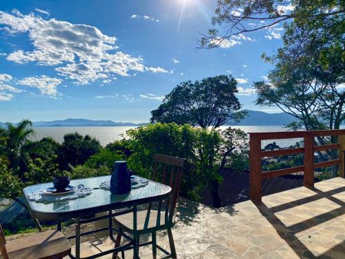 a table and chairs on a patio with a view of the water at TINY HOUSE - Privacidade e Vista Exclusiva da Ilha in Palhoça