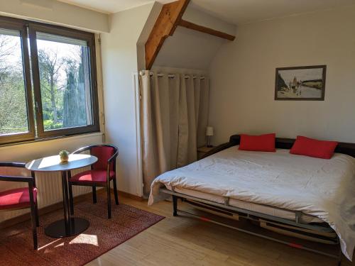 1 dormitorio con cama, mesa y ventana en Appartement Le Louis Dort au calme, en Équemauville