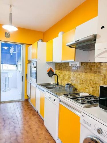 une cuisine avec des placards jaunes et blancs et une cuisinière dans l'établissement César - 4 prs - Parking - Wifi, à Cassis