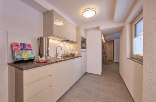 a kitchen with white cabinets and a window at Aparthotel Grischuna in Samnaun