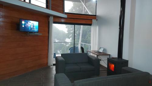a living room with a tv and a chair and a stove at Casa de montaña Arisa in Cartago