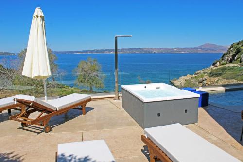 una bañera de hidromasaje y una sombrilla en un patio con vistas al océano en Villa Almy, en Plaka