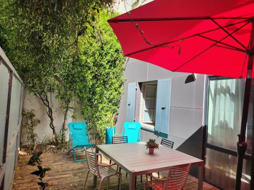 a table and chairs on a patio with a red umbrella at Le jardin de l'horloge in La Rochelle