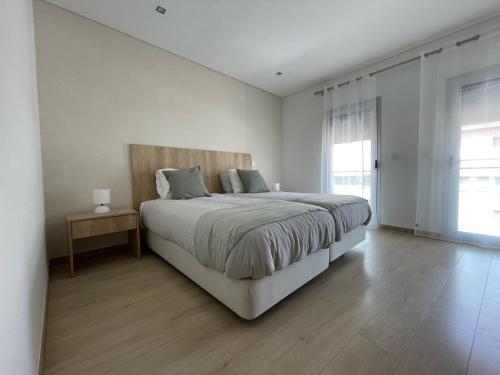 a white bedroom with a large bed and a window at Fátima Apartment - 1min Santuário in Fátima
