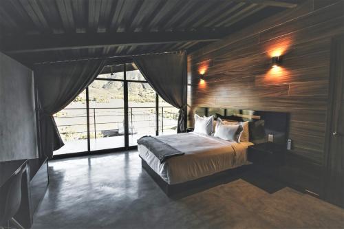 a bedroom with a bed and a large window at Origen75 Loft - Villas - Skypool - Viñedo, Valle de Guadalupe in Valle de Guadalupe
