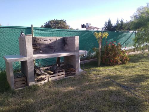 a concrete oven in the grass next to a fence at Cabaña Las Praderas Vistalba in Ciudad Lujan de Cuyo