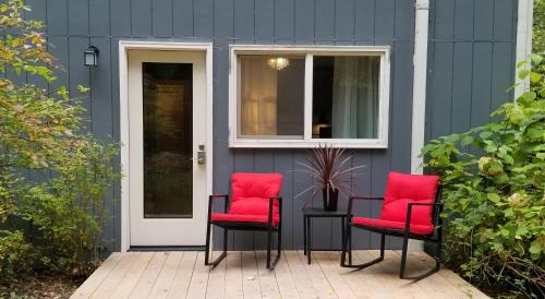 two red chairs sitting on a patio in front of a house at Creekside Bed and Breakfast Guest Room in Deerhorn