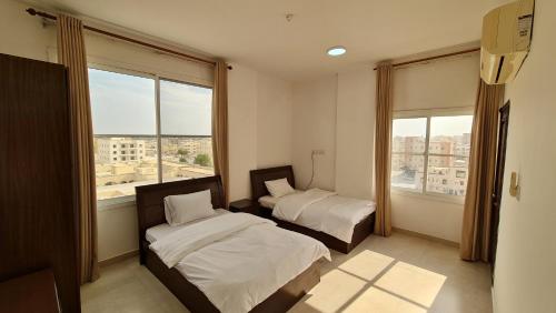 a bedroom with two beds and a large window at هومينج - Homing (شقق مفروشة) in Salalah