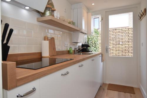 eine Küche mit weißen Schränken und einem Waschbecken in der Unterkunft Casa Feliz in Egmond aan Zee