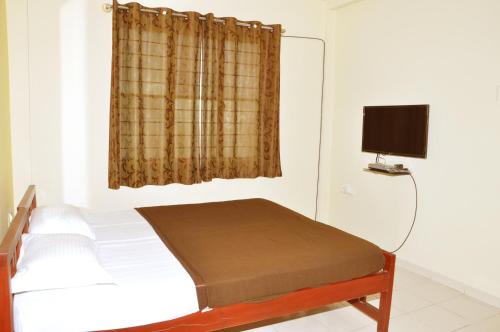 a bedroom with a bed and a window with a television at Vega Residency in Bangalore