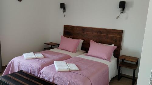 2 camas en una habitación con sábanas rosas y toallas en Quinta do Oratório Agroturismo, en Óbidos