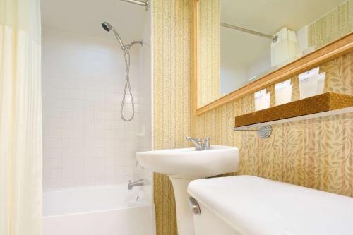 ein Badezimmer mit einem Waschbecken, einem Spiegel und einer Badewanne in der Unterkunft Waikiki Malia in Honolulu