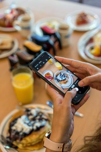 a person holding a cell phone in front of a table with food at Waikiki Malia in Honolulu