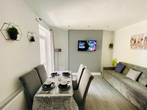 a living room with a table and a couch at Emerald Properties UK 4 bedrooms - Swansea City Centre, close to beaches! in Swansea