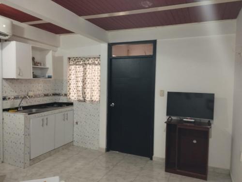 a kitchen with a black door and a tv at El Hogar de Ami in Cali
