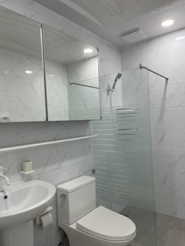 a bathroom with a toilet and a shower and a sink at Mariana Suites in San Roque