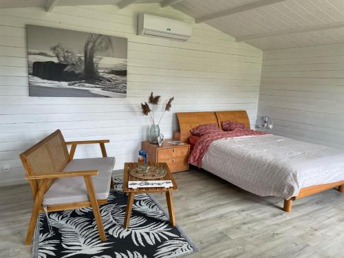 een slaapkamer met een bed, een stoel en een tafel bij « Aux bonheurs Landais » in Linxe