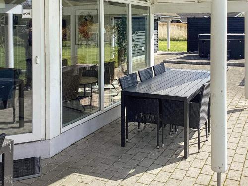 a wooden table and chairs on a patio at 14 person holiday home in Idestrup in Marielyst