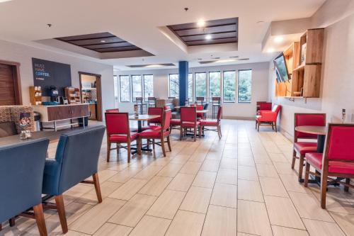 un comedor con sillas rojas, mesas y ventanas en Holiday Inn Express Hotel & Suites Goshen, an IHG Hotel, en Goshen