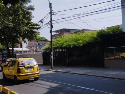 a yellow car is driving down a street at El Hogar de Ami in Cali