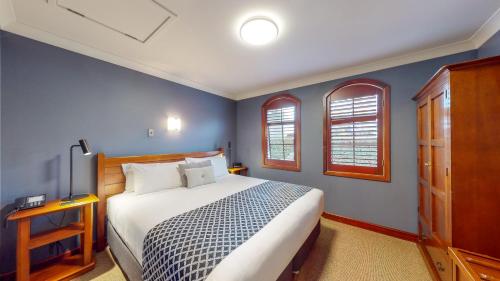 a bedroom with a large bed and two windows at Quantum Lodge Motor Inn in Hamilton