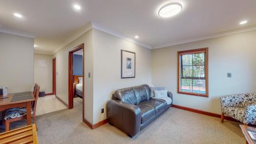 a living room with a leather couch and a desk at Quantum Lodge Motor Inn in Hamilton
