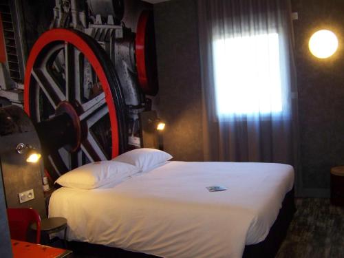 a bedroom with a large bed with a wooden headboard at ibis Styles Vierzon in Vierzon